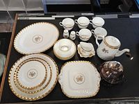 Full set of Minton bone china with rose gold and floral designs, including dinnerware and serveware items arranged on black surface.