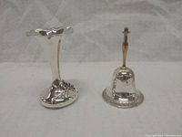 Photo showing silver-plated small vase with floral motifs and silver hand bell side by side