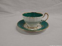 Side view of the Aynsley tea cup and saucer showing green, white, and gold details
