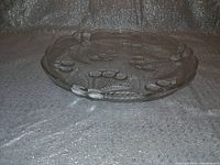 Side angled view showing depth and embossed fruit motifs on vintage clear glass serving plate.