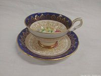 Photo showing vintage Royal Stafford tea cup on matching saucer, displaying detailed blue, gold, and floral design.