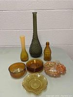 Full view of 10 colored glass decorative pieces including vases, bowls, plates, and a bottle-shaped item.