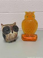 Front view of ceramic owl planter alongside orange glass owl decoration.