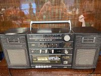 Full view of black JVC boombox with handle, dual speakers, graphic equalizer, tape deck, radio tuner and control knobs.