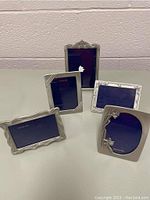 Front view of all five Royal Selangor pewter picture frames arranged together showing their different shapes and decorative details.