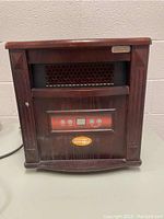 Front view showing wood-finish portable furnace space heater with control panel and metal heating element cover.