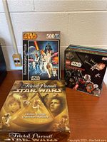 Star Wars Trivial Pursuit Classic Trilogy Collector's Edition board game, Ravensburger 500-piece Star Wars puzzle, and LEGO Star Wars Collection book arranged together