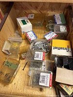 Image showing a wooden box containing various small cardboard and plastic boxes of screws, nails, and hardware components.