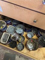 Drawer filled with assorted nails, screws, and hardware stored in multiple coffee cans, glass jars, and containers.