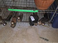 View of all five receiver hitches lined up on metal shelving, showing different sized balls and rust wear.