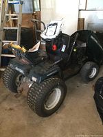 Front angle of Craftsman lawn tractor showing torn seat and detached components, with included parts package.
