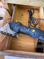 Handheld blue and black MasterCraft Multi Cutter Precision Saw with power cord inside wooden box.