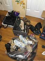 Lot of ladies shoes and purses in bags and bins arranged on the floor, showcasing variety and condition.