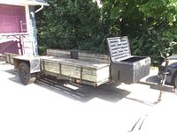 Side view showing overall trailer, wood deck, side rails and storage bin