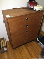 Front view of the vintage 5-drawer teak veneer dresser with round chrome recessed drawer handles, showing condition and wear.