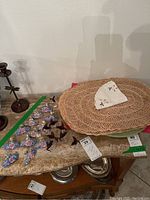 Porcelain card holders arranged on a surface with hummingbird-shaped blown glass napkin rings and woven placemats in background.