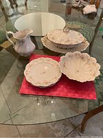 Full set showing pitcher, covered gravy bowl with platter, scalloped bowl, and plates on a glass table.