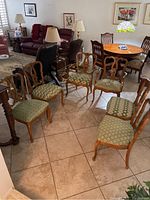 Photo showing six wooden dining chairs arranged in a semi-circle, highlighting the upholstered seats and wooden frames.