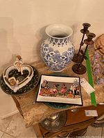Photo of Southwest style platters, porcelain vase, metal candle holders, heart-shaped flower holder, and collectors plates on table.