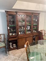 Front view of the dining hutch showing glass door display sections on top and wood cabinet doors and drawers below, some doors open with no contents inside.