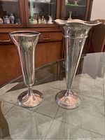 Two sterling silver vases placed on glass table, showing relative sizes and designs