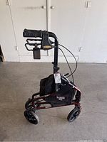 Side view of the three-wheeled walker showing the adjustable hand grips, fabric bag, and wheel construction.