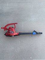 Full view of the TORO red corded electric yard blower with black directional nozzle.