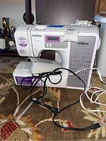 Front view of Brother Project Runway CE8080PRW sewing machine with power cords and accessory tray.