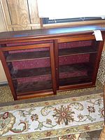 Front view of the wooden display cabinet showing two glass doors and red floral interior.