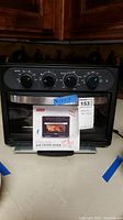 Front view of Dash Everyday Air Fryer Oven with control knobs and instruction manual on counter