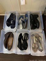 Six pairs of ladies shoes in plastic bins, displaying a variety of styles and colors.