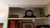 Shelf with mantel clock, decorative box, and green glass pitcher, showing lot contents