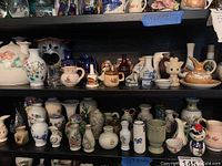 Shelf with multiple shelves filled with mini ceramic vases, pitchers, and figurines in various colors and floral designs.