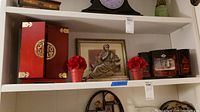 Wide shelf view showing all items including statue, framed art, jewelry boxes, flower pots.