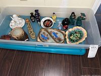 Photo shows various small ceramic items including mini white tea set, vases, decorative bowls, and figurines inside a storage bin.