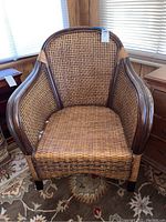 Front view of wicker armchair showing woven cane seat and dark wooden frame.