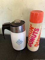 Photo showing white Corning coffee carafe with black handle and blue floral design alongside a vintage Dunkin Donuts thermos with orange lid and branding.
