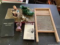 Overview of all items on a flat surface showing the figurines, washboard, cassette tape, book, and small wooden cup figurine.