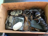 Box containing game controllers, microphone, P-Touch label maker, mouse, calculator and scissors.