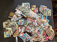 Wide assortment of scattered 1970s baseball cards on a table, showing variety of players and teams.