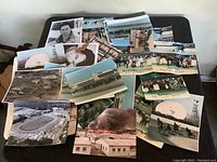 Photo showing a dispersed collection of horse racing photographs lying on a table. Includes racing action shots, an aerial photo of a racetrack, some portraits, and a color photo of a fire at buildings.