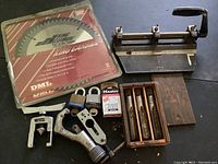 Photo of Dewalt circular saw blade, sheet metal notcher, master padlocks both loose and in packaging, set of 4 wood handled chisels in box, hand clamp, and metal measuring tool.