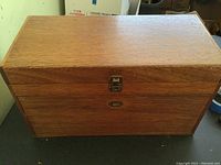 Closed oak machinist tool box showing sturdy wooden construction with a hinged top and latch.