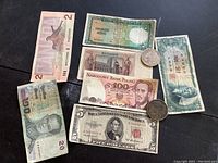 Various foreign banknotes and coins laid out on a surface showing multiple currencies from Poland, Vietnam, Germany, and Japan with three silver coins.