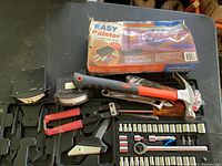 Photo of multiple socket tools, hammer, rivet gun, clamps, and boxed painter's tool on a surface.