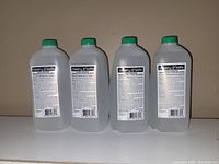 Four large translucent plastic bottles of Clean 'n' Safe hand sanitizer with green caps, showing rear labels with product details.