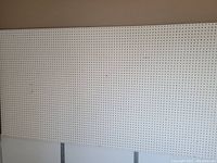 Photo of an 8-foot rectangular pegboard panel with evenly spaced holes in a beige color.