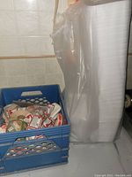 Photo showing tall stack of white styrofoam inserts next to a blue crate filled with butcher labels.