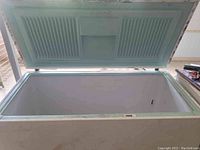 Open top view of empty chest freezer interior showing molded section and some rust and wear along edges