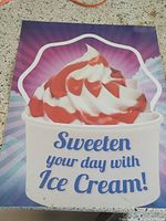 Front of laminated sign showing an image of soft serve ice cream with strawberry sauce and text 'Sweeten your day with Ice Cream!'